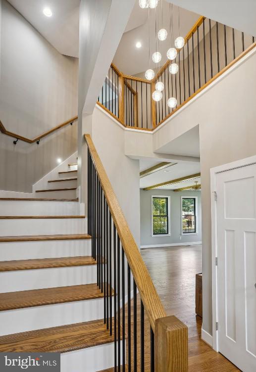 stairway featuring a high ceiling, a notable chandelier, and hardwood / wood-style floors