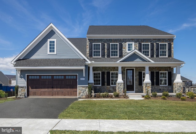 craftsman-style home with a garage, covered porch, and a front lawn