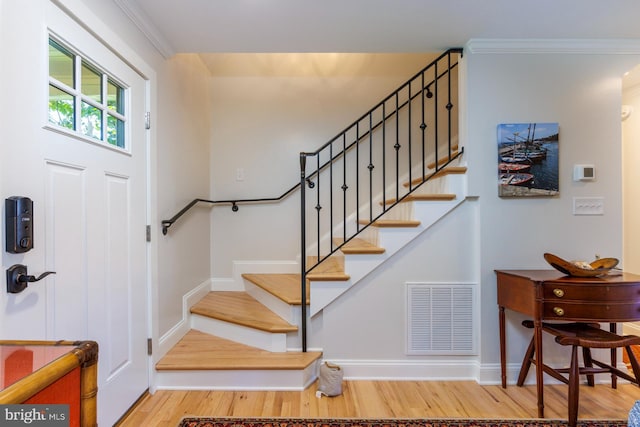 entrance foyer with ornamental molding and light hardwood / wood-style floors