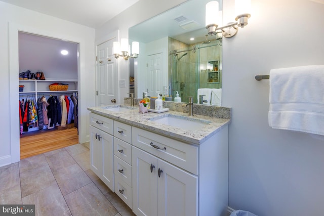 bathroom with dual sinks, a shower with shower door, large vanity, and tile flooring