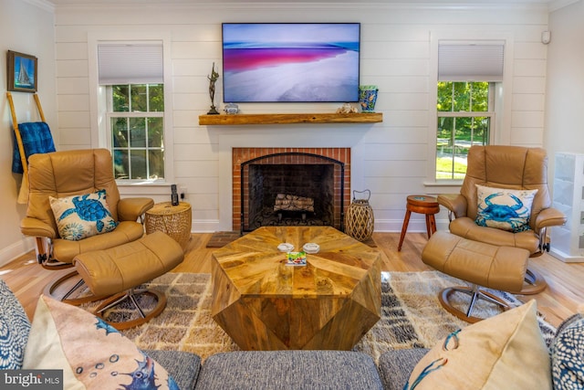 living room with light hardwood / wood-style floors, ornamental molding, and a fireplace