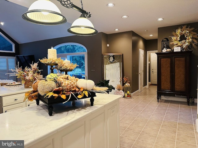 interior space with lofted ceiling, light tile floors, white cabinetry, and light stone counters