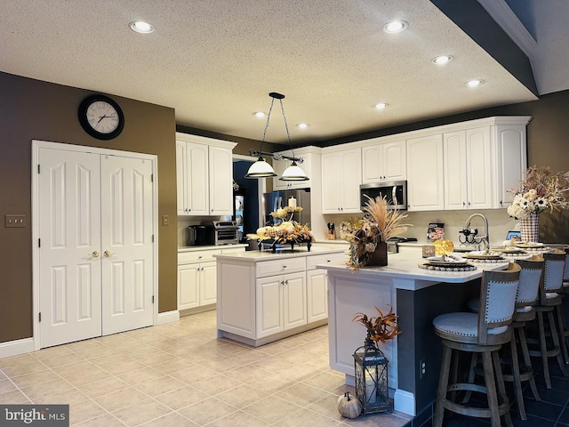 kitchen featuring appliances with stainless steel finishes, pendant lighting, and white cabinetry