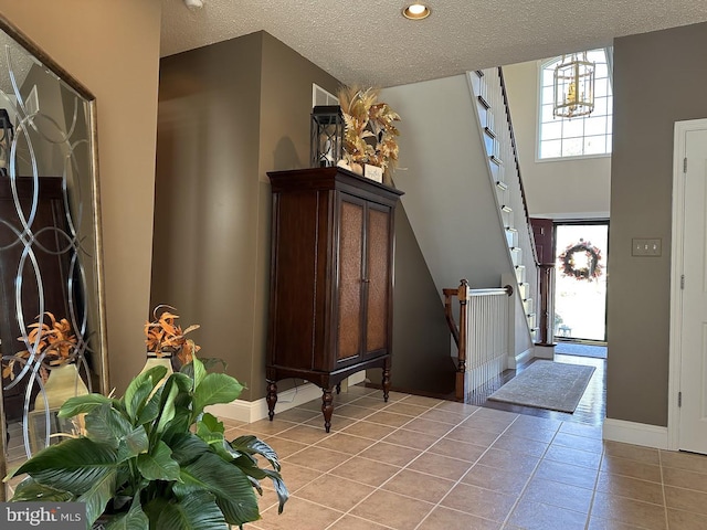 entryway with light tile floors, a textured ceiling, and a chandelier