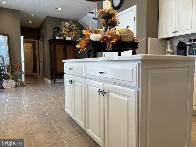 kitchen with light tile floors, white cabinetry, and a textured ceiling