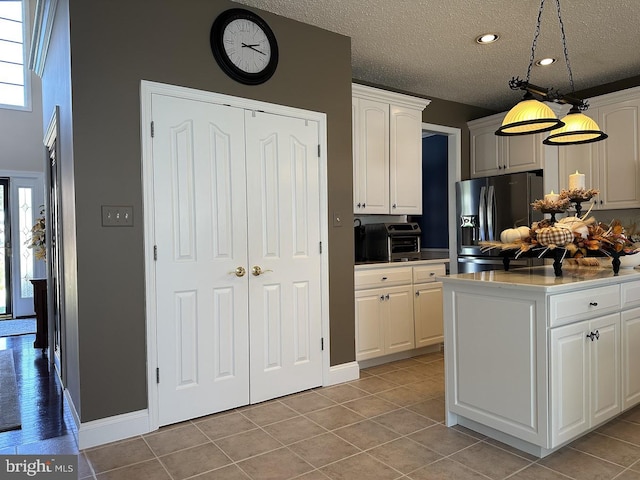 kitchen featuring hanging light fixtures, stainless steel fridge, white cabinets, and light tile floors