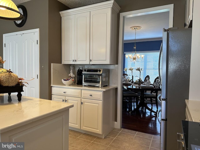 kitchen featuring an inviting chandelier, white cabinetry, hanging light fixtures, and fridge