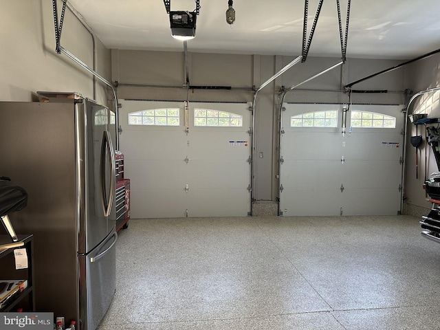 garage with stainless steel fridge and a garage door opener