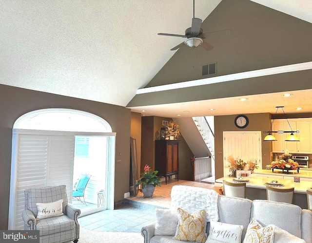 tiled living room with a textured ceiling, ceiling fan, and high vaulted ceiling