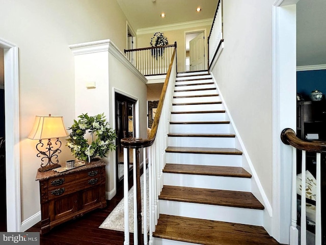 stairs with dark hardwood / wood-style floors, ornamental molding, and a high ceiling