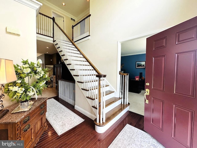 foyer featuring dark hardwood / wood-style flooring, ornamental molding, and a towering ceiling