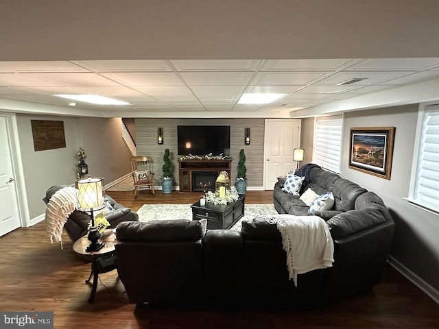 living room with a paneled ceiling and dark hardwood / wood-style floors