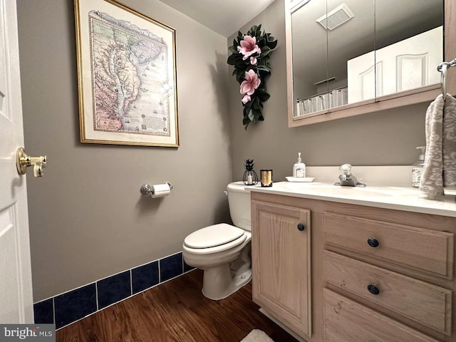 bathroom with toilet, vanity, and wood-type flooring