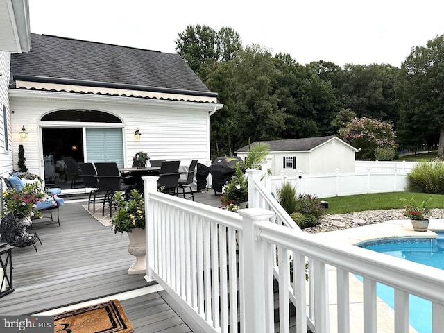 wooden deck with a fenced in pool and an outdoor structure