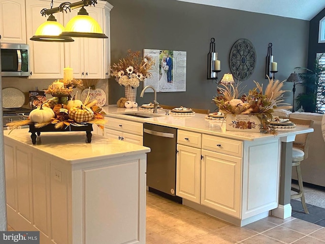 kitchen featuring sink, light tile floors, white cabinets, stainless steel appliances, and a center island