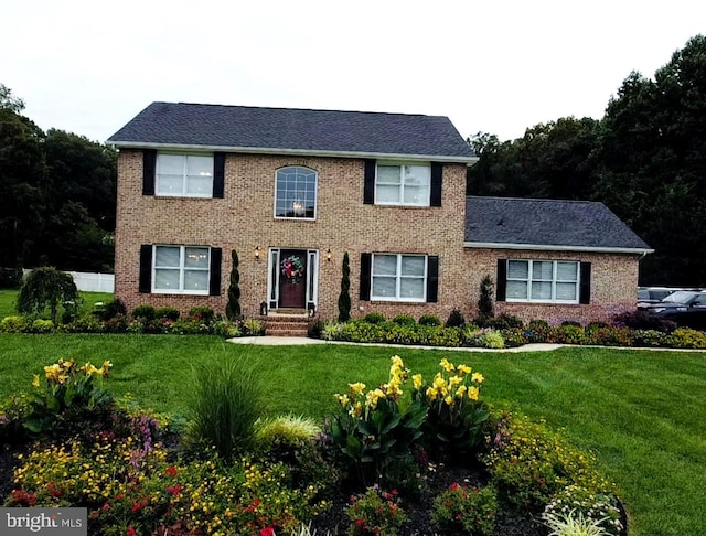 colonial-style house featuring a front lawn