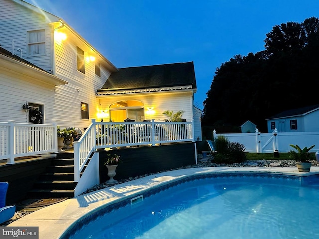 pool at night featuring a wooden deck