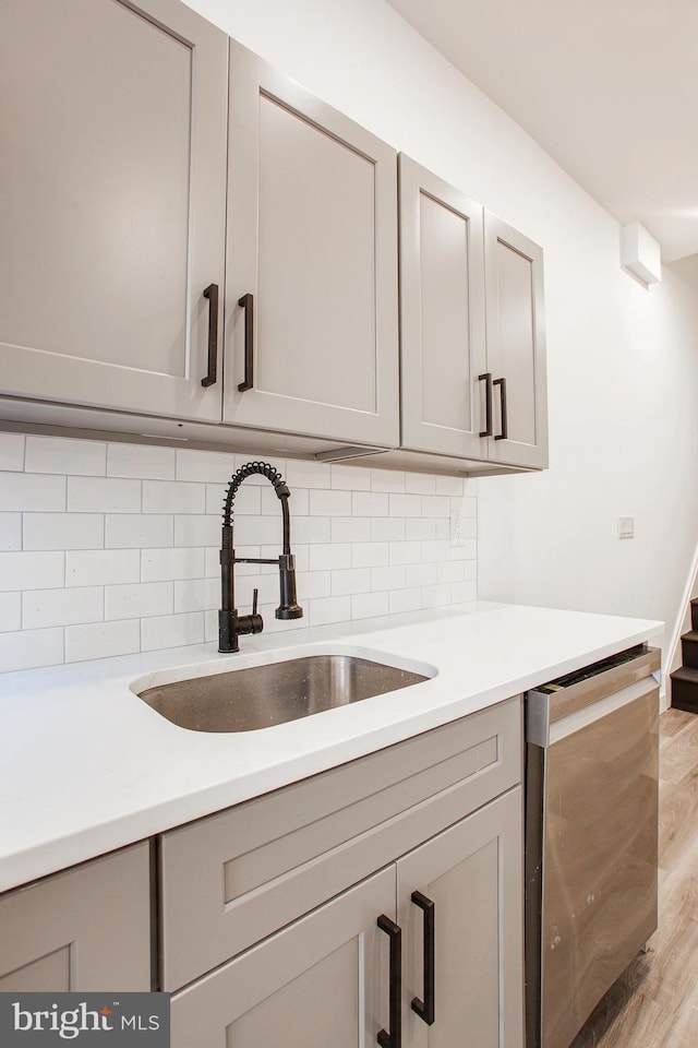 kitchen featuring gray cabinets, sink, light hardwood / wood-style flooring, and tasteful backsplash