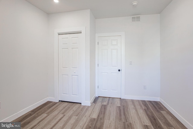 unfurnished bedroom with a closet and light hardwood / wood-style flooring