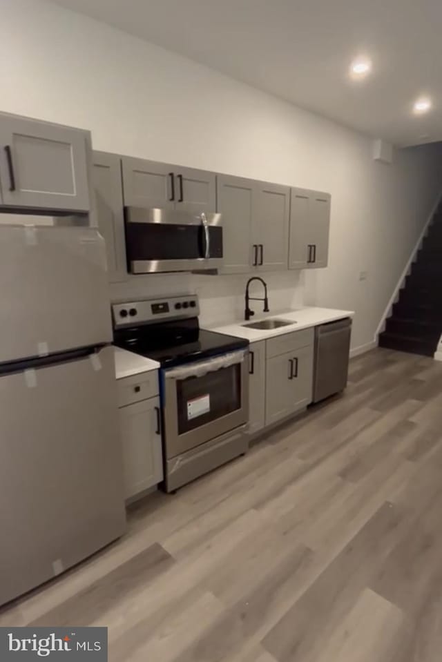 kitchen featuring light hardwood / wood-style flooring, gray cabinetry, sink, and stainless steel appliances