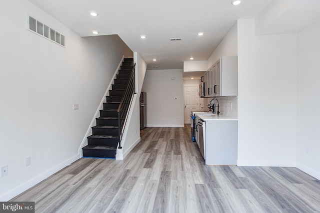 kitchen with gray cabinets, light wood-type flooring, and backsplash