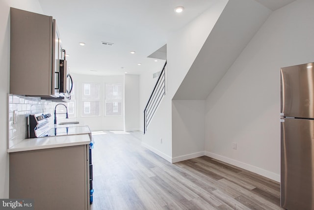 kitchen featuring appliances with stainless steel finishes, decorative backsplash, and light hardwood / wood-style flooring