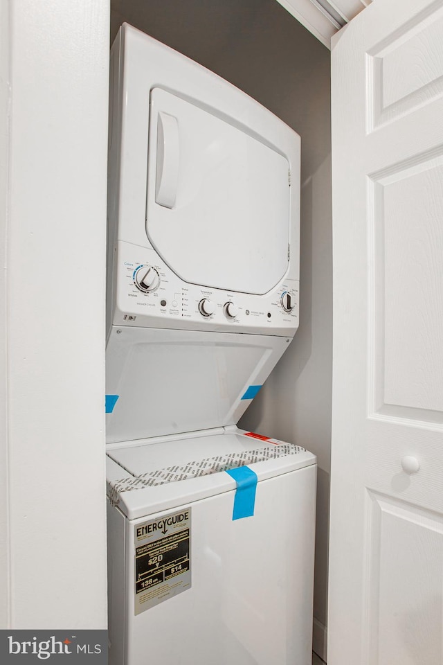 clothes washing area with stacked washing maching and dryer