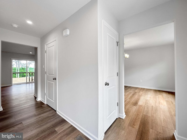 corridor featuring hardwood / wood-style floors and a notable chandelier