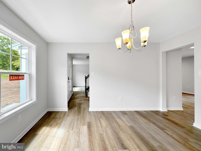 unfurnished dining area featuring wood-type flooring and an inviting chandelier