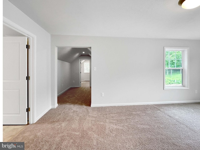 carpeted empty room with vaulted ceiling