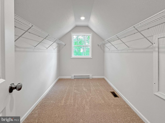 spacious closet featuring carpet flooring, lofted ceiling, and a baseboard heating unit