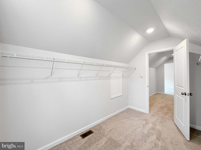 spacious closet featuring light colored carpet and vaulted ceiling