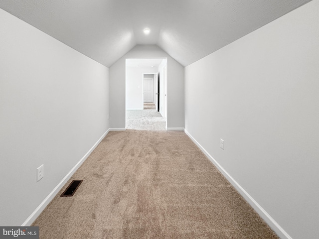 additional living space featuring carpet and vaulted ceiling