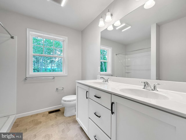 bathroom with vanity, toilet, walk in shower, and a healthy amount of sunlight