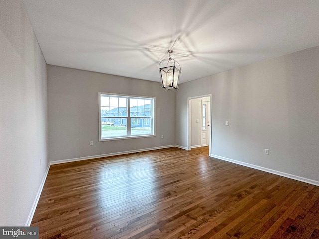 unfurnished room featuring a chandelier and dark hardwood / wood-style floors