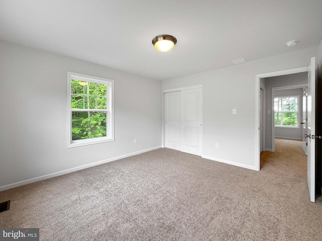 unfurnished bedroom with carpet flooring, multiple windows, and a closet