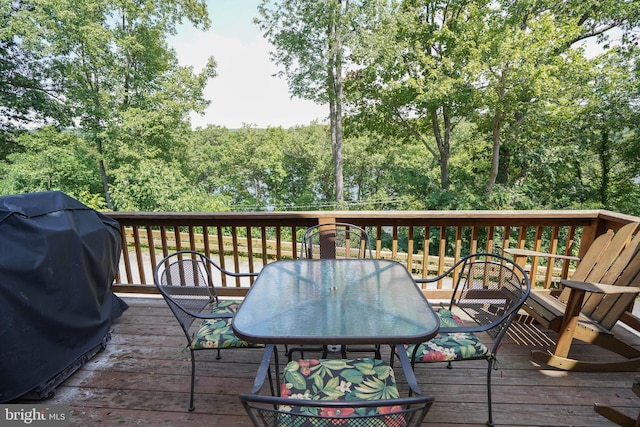 wooden terrace with outdoor dining space and a grill