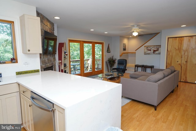 kitchen featuring open floor plan, a peninsula, dishwasher, and white cabinets