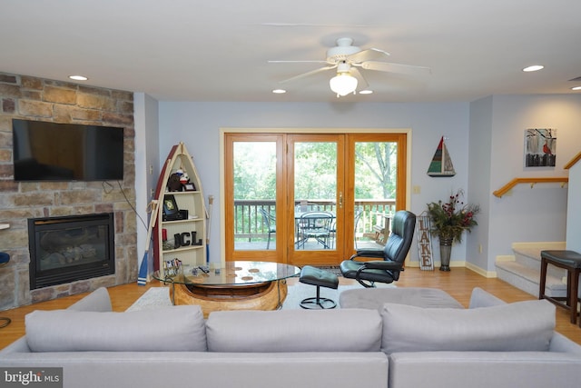 living room featuring a fireplace, ceiling fan, and light hardwood / wood-style floors