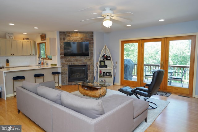 living room with ceiling fan, a fireplace, light hardwood / wood-style floors, and a healthy amount of sunlight