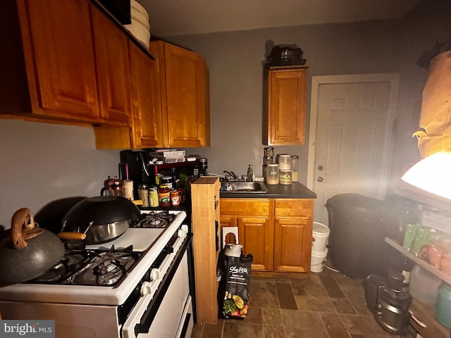 kitchen featuring dark tile floors, sink, and range with gas cooktop