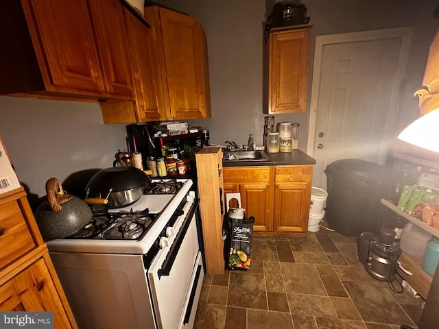 kitchen with dark tile flooring, sink, and gas range gas stove