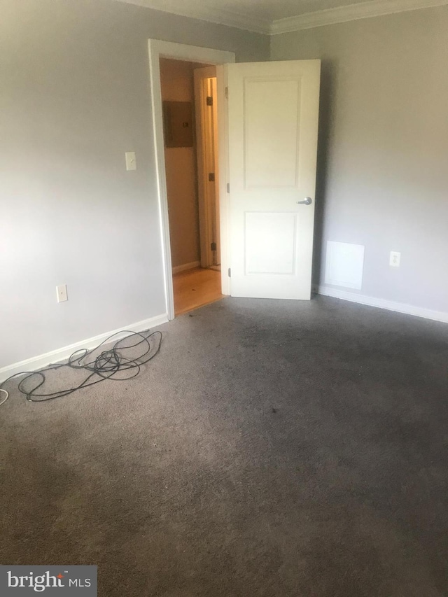 unfurnished room featuring crown molding and dark colored carpet