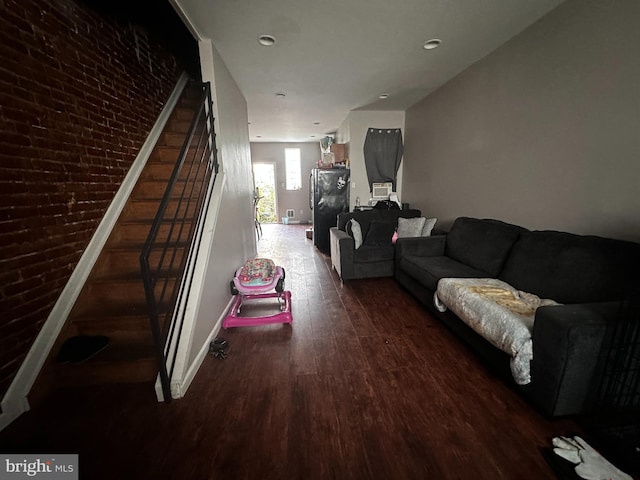 living room featuring brick wall and dark hardwood / wood-style floors