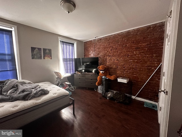 bedroom featuring brick wall and dark hardwood / wood-style floors