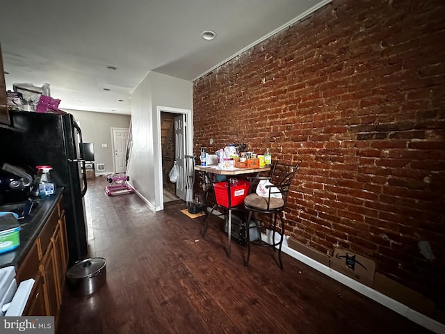 interior space featuring black fridge, brick wall, and dark hardwood / wood-style flooring