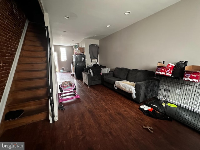 living room with dark hardwood / wood-style flooring and brick wall