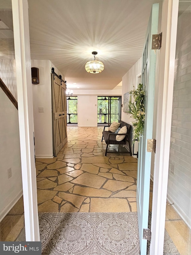 corridor featuring a barn door and a chandelier