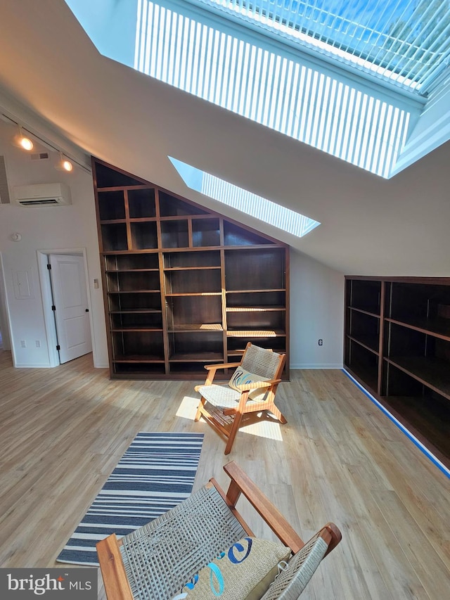 interior space featuring a skylight, light wood-type flooring, a towering ceiling, and rail lighting