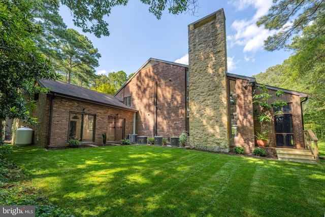 rear view of property with central AC and a yard